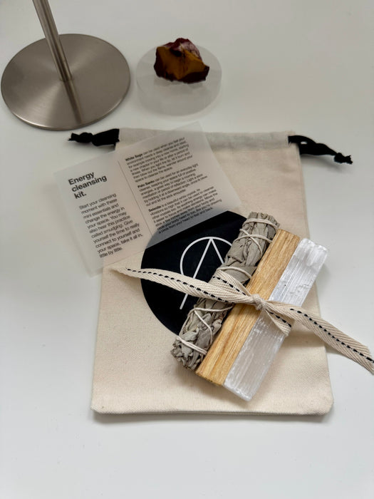 Energy cleansing kit with sage, crystal, and information card on a white surface